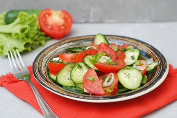 Tomato and cucumber salad vegan food with fork gray textured cement background