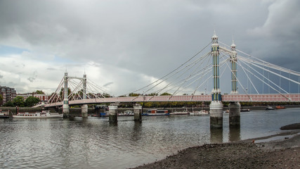 Albert Bridge over river Thames in London on gray overcast day. It connects Chelsea to Battersea and was opened in 1873