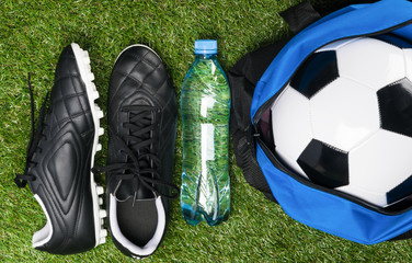 Shoes and ball for playing football on a green lawn