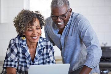 Senior African American couple using a computer in the kitchen together