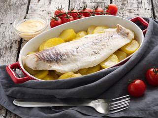 Fish cod baked in the oven with potatoes, diet healthy food. Dark old wooden rustic gray background, side view