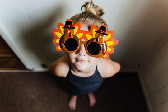Cute toddler girl wearing Thanksgiving turkey sunglasses.