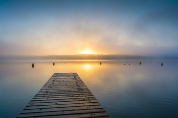 Fototapeta na wymiar Sonnenaufgang am See mit Steg im Nebel