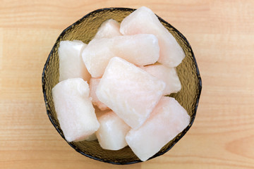 Frozen Pangasius, Dory fish cut in cube in glass bowl, top view. Fillet of fresh water fish in chunk