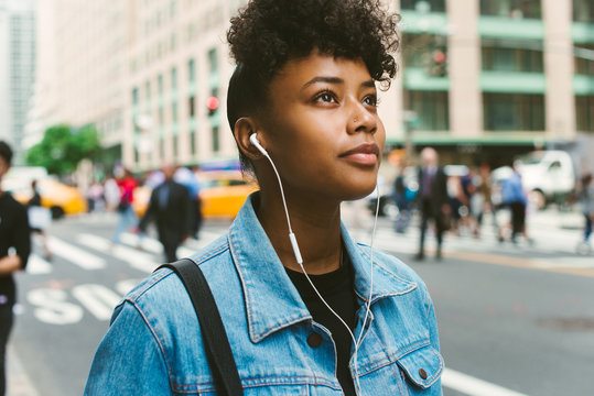 Young woman listening to music on headphones in city
