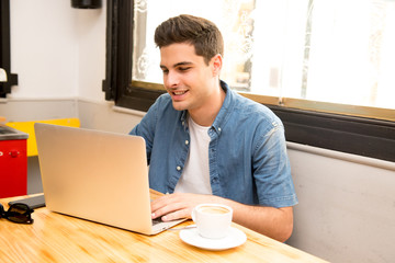 young student man working and studying on computer in coffee shop