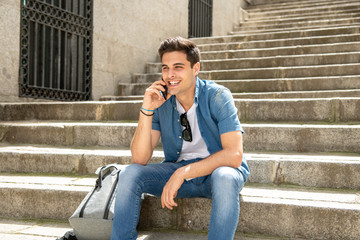 Fototapeta na wymiar Handsome modern happy young man talking on his smart phone outside in the city.