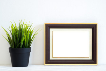 Blank picture frame on white table and white wall