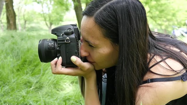 Young woman entrepreneur photographer at working process shooting outdoors in nature