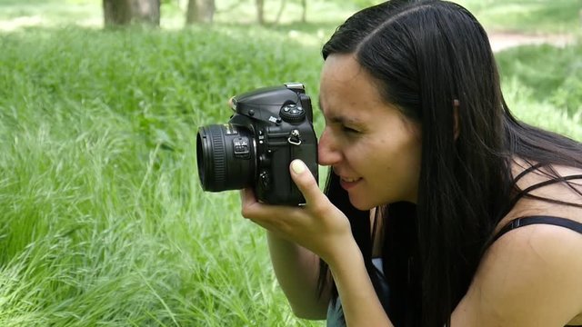 Young woman entrepreneur photographer at working process shooting outdoors in nature