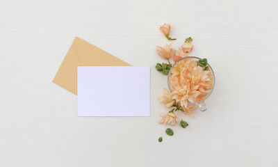 Postcard mockup whith flowers and envelope, on wooden background