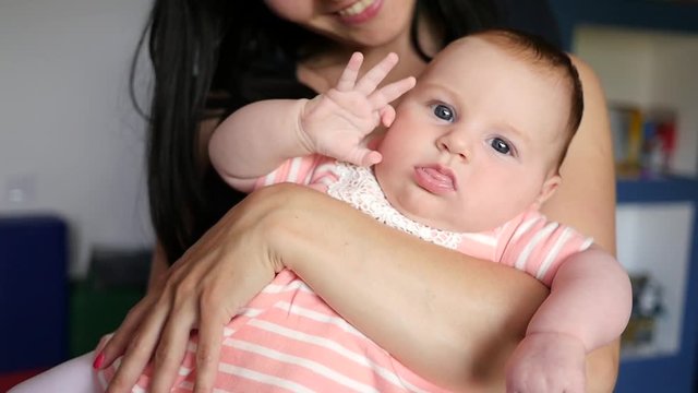 Young mother holding in arms her cute infant baby daughter, slow motion
