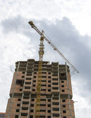 Construction crane against the background of the cloudy sky