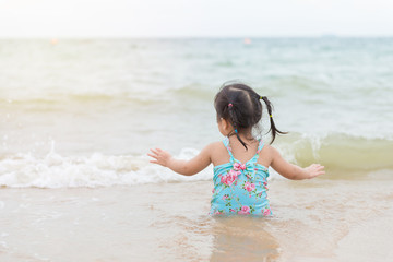 little girl sitting and playing on the beach with sand