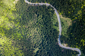 Winding road from high mountain pass, in summer time. Aerial view by drone . Romania	