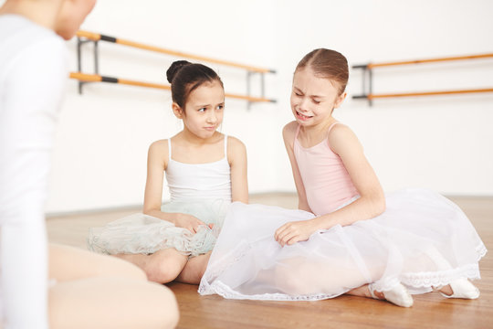 Girls with strict hairstyle and white tutu listening critic of teacher and crying in dancing school