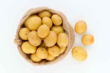 Sack of fresh raw potatoes on wooden background, top view