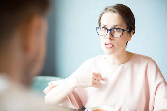 Attractive woman in stylish glasses having serious conversation with employee. 