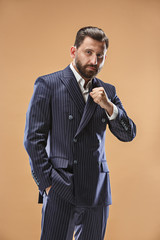 Male beauty concept. Portrait of a fashionable young man with stylish haircut wearing trendy suit posing over pastel background.