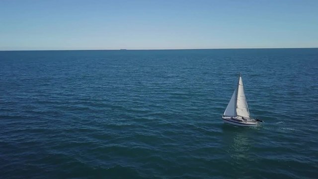 Lonely sailboat plows the expance of the ocean, aerial shoot. Yacht from drone.