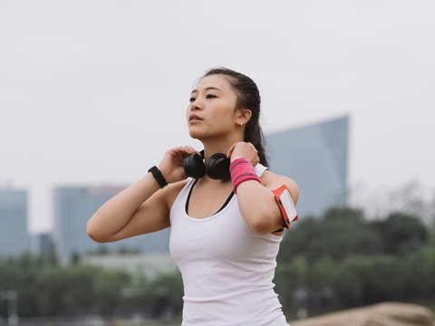portrait of sporty woman standing at lakeside with a black headphone on her neck