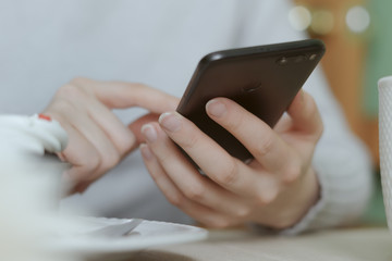 close-up hand holding phone white screen over work table