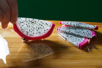 The girl takes a slice of cut pythaya