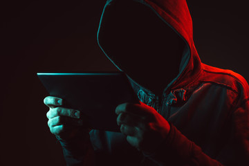 Faceless man with hoodie holding tablet computer