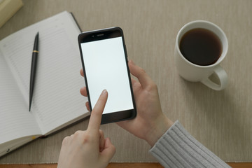 Girl with a phone in her hands sitting on the wooden floor.top view