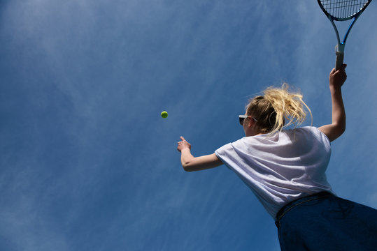 Woman serving tennis ball