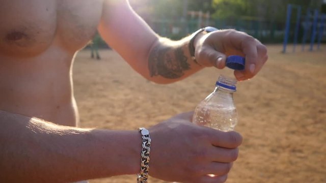 Young attractive strong guy portrait drink clean water from bottle after sports workout