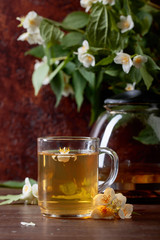 Green tea with jasmine in cup and teapot on old wooden table.