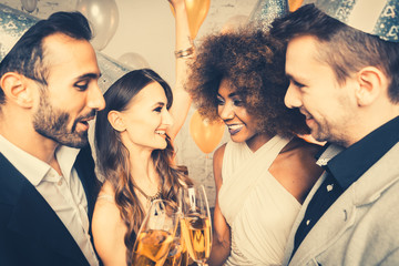 Men and women celebrating birthday or new years party while clinking glasses with sparkling wine