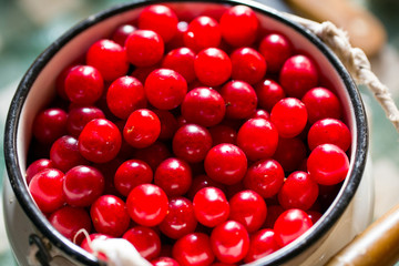 Cherries in white metal cans on a wooden table