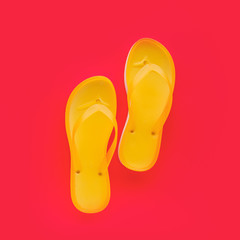 Yellow beach flip flops on neon pink background
