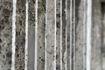 Fototapeta premium Stone fence with parallel concrete poles and old green moss