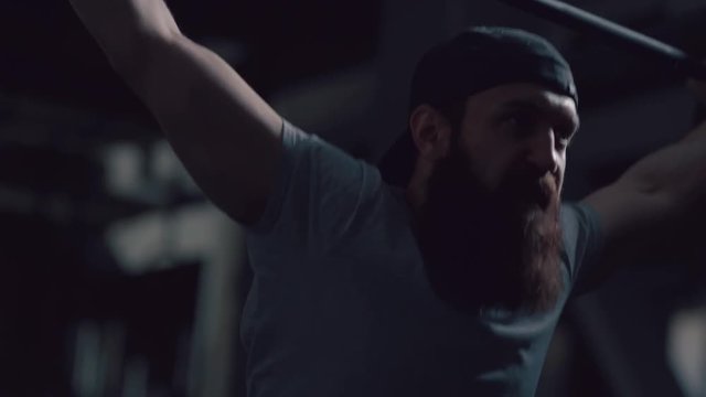 Brutal athlete lifts the bar above himself, performing a jerk, a spinning push. A man with a beard is engaged in weightlifting on a dark background, portrait. Concept strength, power, playing sports.