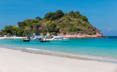 Fototapeta na wymiar Tourists with yellow life jackets are getting out of a motor boat into the turquoise blue water at the beautiful white sandy Long Beach (Pasir Panjang) of Redang Island in Terengganu, Malaysia.