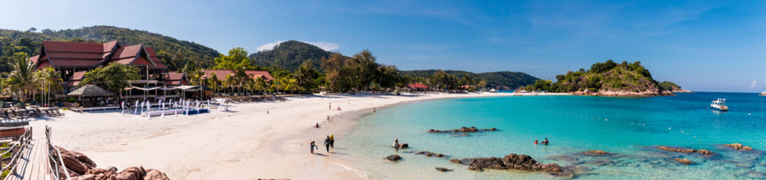 Beautiful panoramic view of Long Beach (Pasir Panjang) on Redang Island in Terengganu, Malaysia. Tourists enjoying their leisure time along the white powdery sand beach and crystal clear blue water.