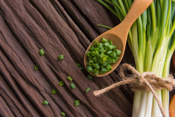 Spring onions also known as salad onions, green onions or scallions on wood background