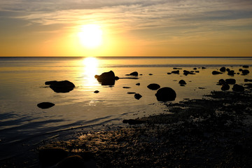 dramatic sunset over the calm sea shore with rocks