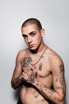 Tattooed shirtless young man portrait isolated over white wall