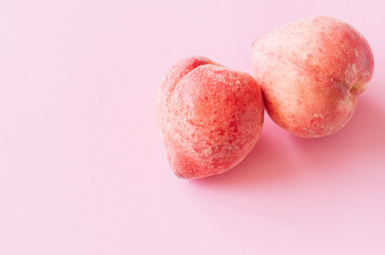 Two fresh ripe peaches on a pink background. Organic food concept. Close up.
