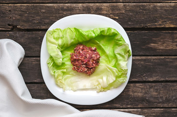 Cabbage roll on the white plate. Raw minced pork with beef in cabbage green leaves.