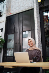 a malay girl at cafe doing work with laptop