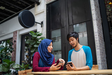 a muslim married couple in a cafe with a laptop