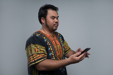 portrait of malay man using phone in gray background