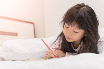 little girl lying on the bed and reading a book