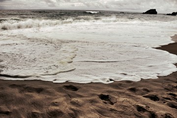 Brave ocean, rock formations and cloudy drama sky on the beach