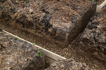 trench with rubble and formwork, which is prepared for pouring the foundation